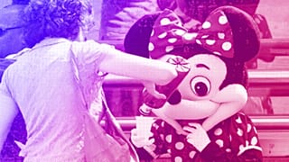 A woman stops to give water to a person dressed in a Mini Mouse costume, one of many who work posing for tourist photos in Madrid, August 2012