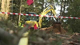 Mit schwerem Gerät wird nach den Überresten der Erschossenen gegraben.