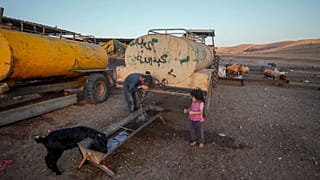 بدو فلسطينيون يشربون الماء من صهريج بالقرب من قرية بردلة في غور الأردن، 8 أغسطس 2023