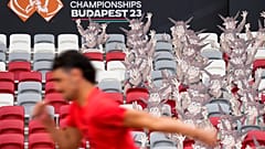 An athlete runs past cutouts of the games' mascot, Youhuu, a native Hungarian sheep, at the National Athletics Centre, Budapest, August 18, 2023