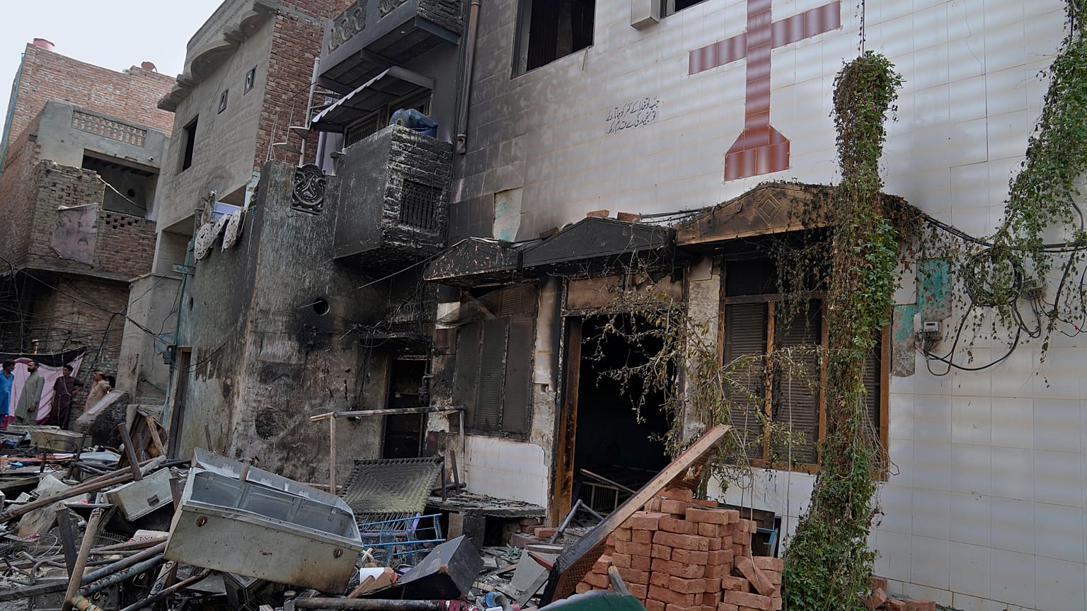 السكان ينظرون إلى أنقاض المنازل والكنيسة التي دمرها حشد من المسلمين الغاضبين في منطقة مسيحية في جرانوالا