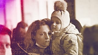 A woman holds her daughter as they try to get on a train at the Kyiv station, 4 March 2022
