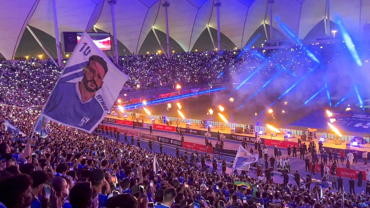 مشجع يلوح بعلم يحمل صورة المهاجم البرازيلي نيمار في استاد الملك فهد الدولي بالرياض.