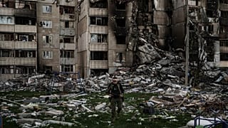 یک سرباز اوکراینی در میان آوارهای ساختمانی که توسط بمباران‌های متعدد روسیه در نزدیکی خط مقدم در خارکیف اوکراین آسیب دیده است، ۲۵ آوریل ۲۰۲۲. 