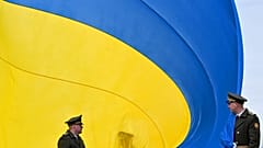 FILE - Ukrainian servicemen hold a huge national flag  near Kyiv, on March 31, 2023.