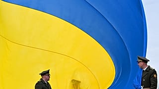 FILE - Ukrainian servicemen hold a huge national flag near Kyiv, on March 31, 2023.