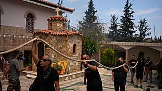 Пожарные тушат огонь в монастыре Святой Параскевы Пятницы в греческом городе Ахарне, 23 августа 2023 г.