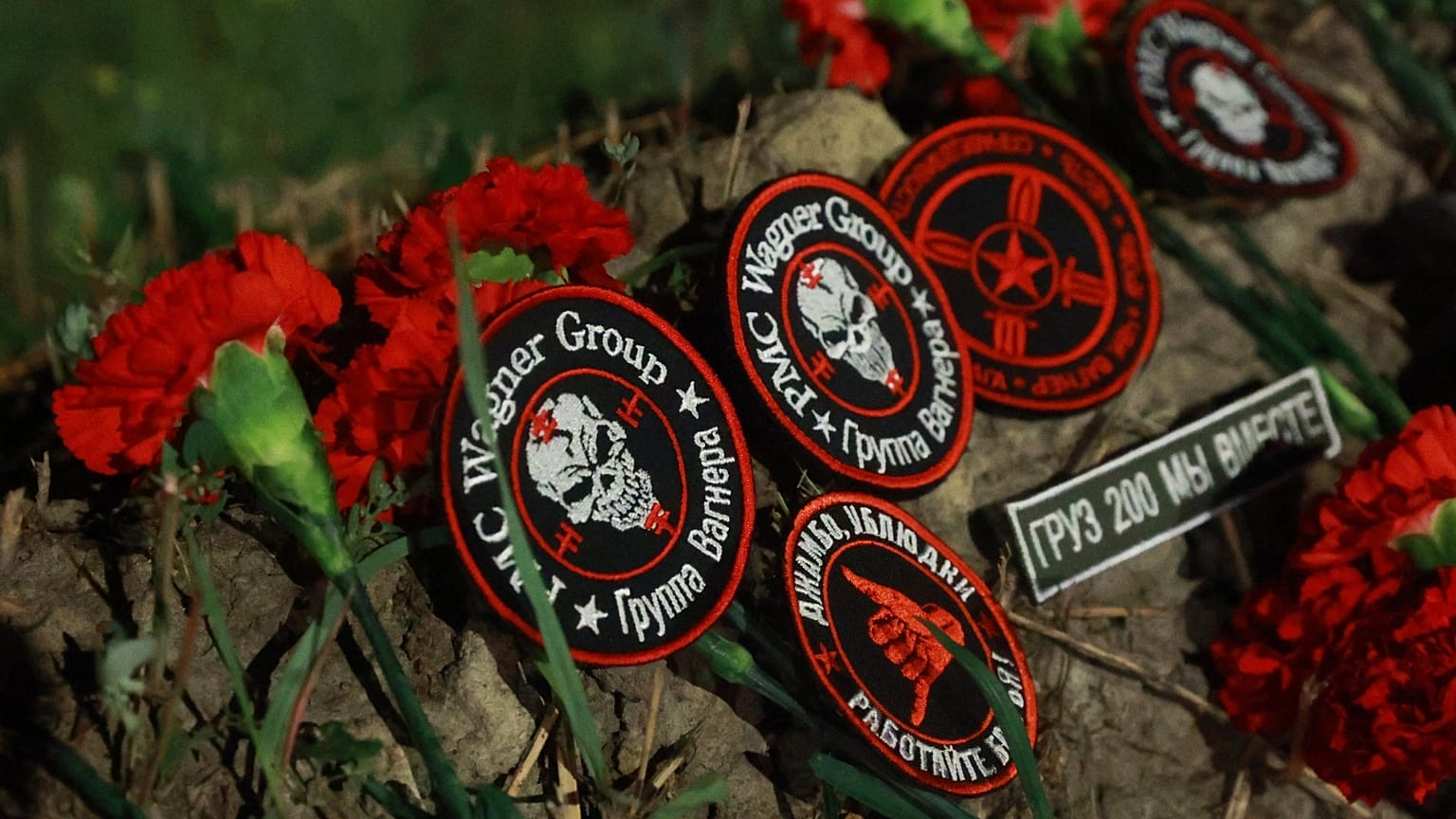 Flowers and patches bearing the logo of private mercenary group Wagner are seen at the makeshift memorial in front of the "PMC Wagner Centre" in Saint Petersburg, 24 August 