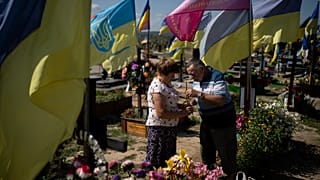 Kateryna and Oleh light a candle at son's grave, who died fighting in the war as Ukrainians mark Independence Day in Kharkiv, Ukraine, Thursday, Aug. 24, 2023