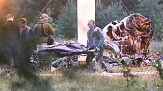 Люди выносят мешок с телом из-под обломков разбившегося самолета в районе деревни Куженкино (Россия). Предполагается, что на борту самолета находился начальник Вагнера Евгений Пригожин.
