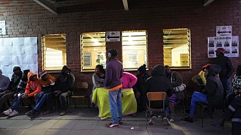 People sit outside a polling station in Harare, Thursday, Aug. 24 ,2023. Voting is still underway in Zimbabwe. 