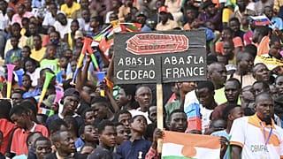 Homem segura cartaz onde se lê: "Abaixo França, abaixo a CEDEAO", Nyamei, 26 de agosto