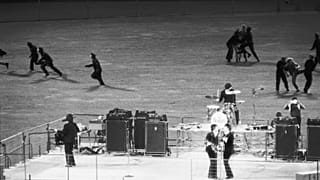 Policemen clear the field of enthusiastic fans as The Beatles perform on a bandstand in Candlestick Park, San Francisco
