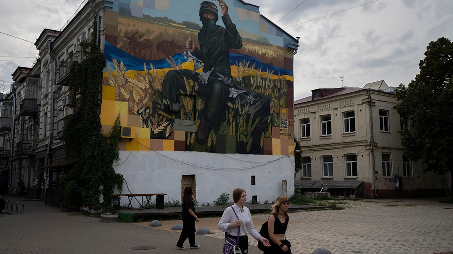 Des gens passent devant une œuvre d'art sur le côté d'un immeuble résidentiel, à Kiev, en Ukraine, le samedi 26 août 2023.