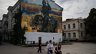 Des gens passent devant une œuvre d'art sur le côté d'un immeuble résidentiel, à Kiev, en Ukraine, le samedi 26 août 2023.