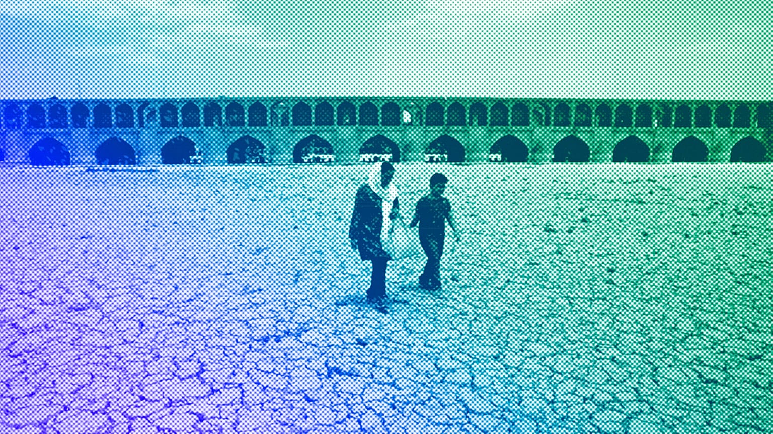 A woman and a boy walk on the dried up riverbed of the Zayandeh Roud river that no longer runs in Isfahan, July 2018