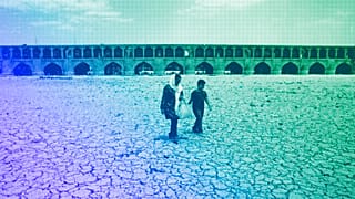 A woman and a boy walk on the dried up riverbed of the Zayandeh Roud river that no longer runs in Isfahan, July 2018