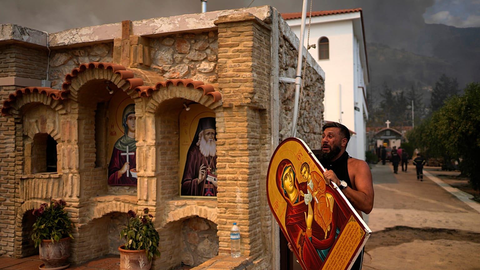 A man carries a saint Mary with Jesus icon to save it from a wildfire at Agia Paraskevi Christian Orthodox monastery in Acharnes a suburb of northern Athens, Greece.