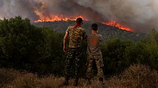 Dois homens assistem às chamas que lavram na região grega de Alexandrópolis