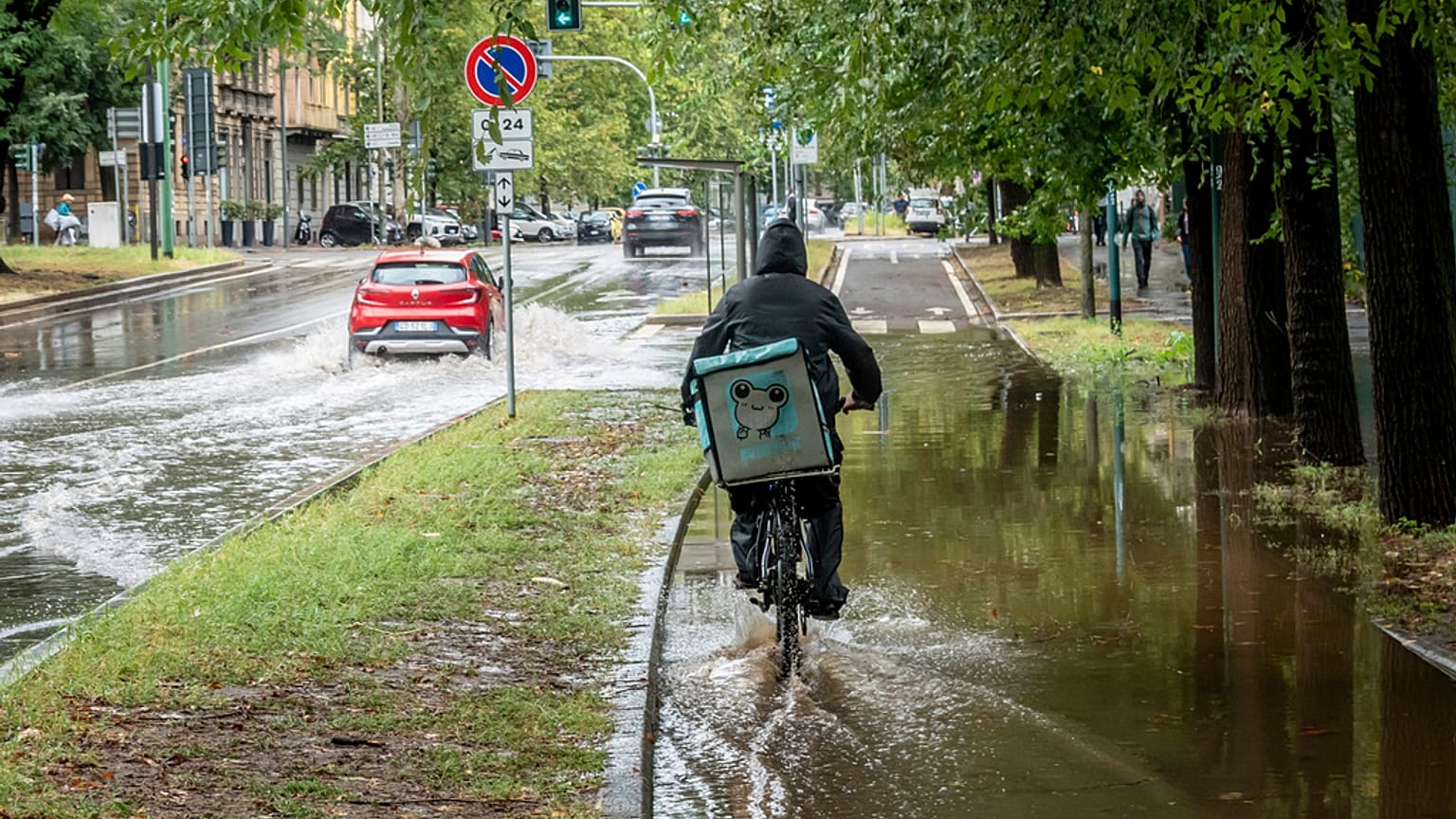 Un ciclista recorre una calle inundada en la zona de Sempione de Milán, Italia, el lunes 28 de agosto de 2023.
