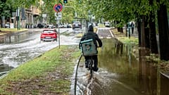 Un ciclista recorre una calle inundada en la zona de Sempione de Milán, Italia, el lunes 28 de agosto de 2023.