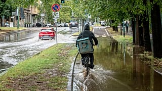 Un ciclista recorre una calle inundada en la zona de Sempione de Milán, Italia, el lunes 28 de agosto de 2023.