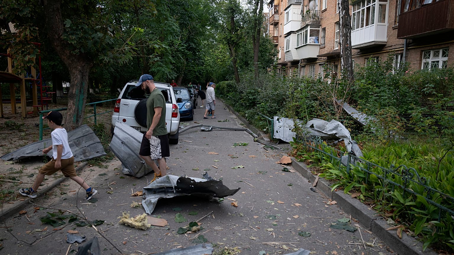 Residentes locales pasan junto a los escombros que cayeron de su casa dañada tras un ataque con cohetes rusos en Kiev, Ucrania, el miércoles 30 de agosto de 2023.