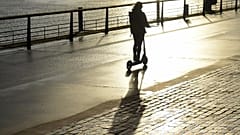 Woman riding an electric scooter, an urban mode of transport that has sparked debates in some cities