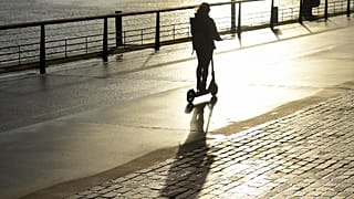 Woman riding an electric scooter, an urban mode of transport that has sparked debates in some cities