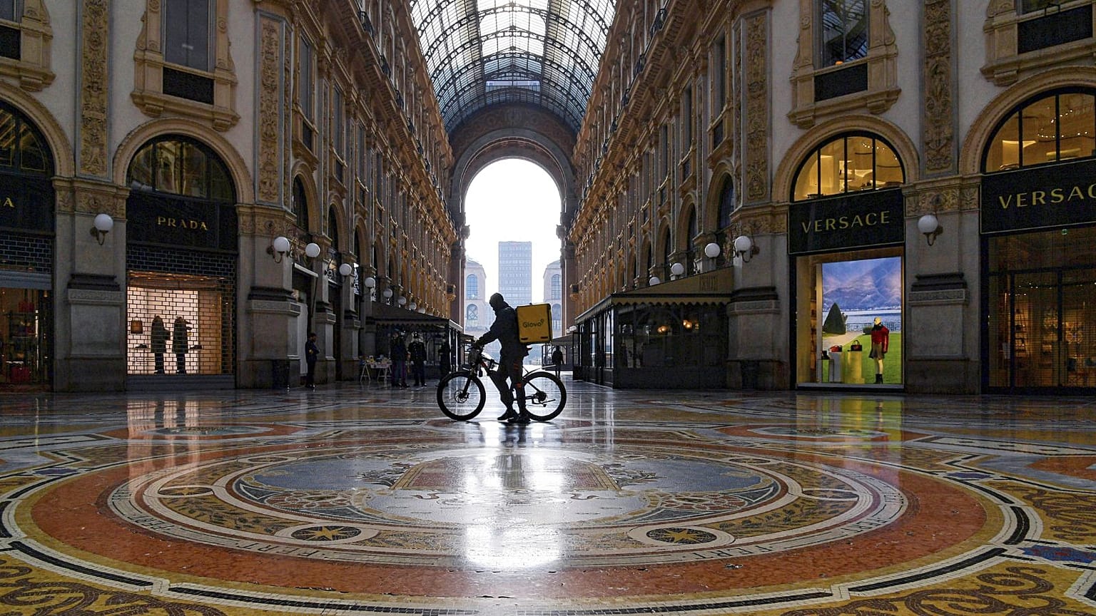 6 Kasım 2020 tarihli bu dosya fotoğrafında, İtalya'nın Milano kentindeki Vittorio Emanuele alışveriş pasajında bir yemek dağıtımcısı bisikletini itiyor.