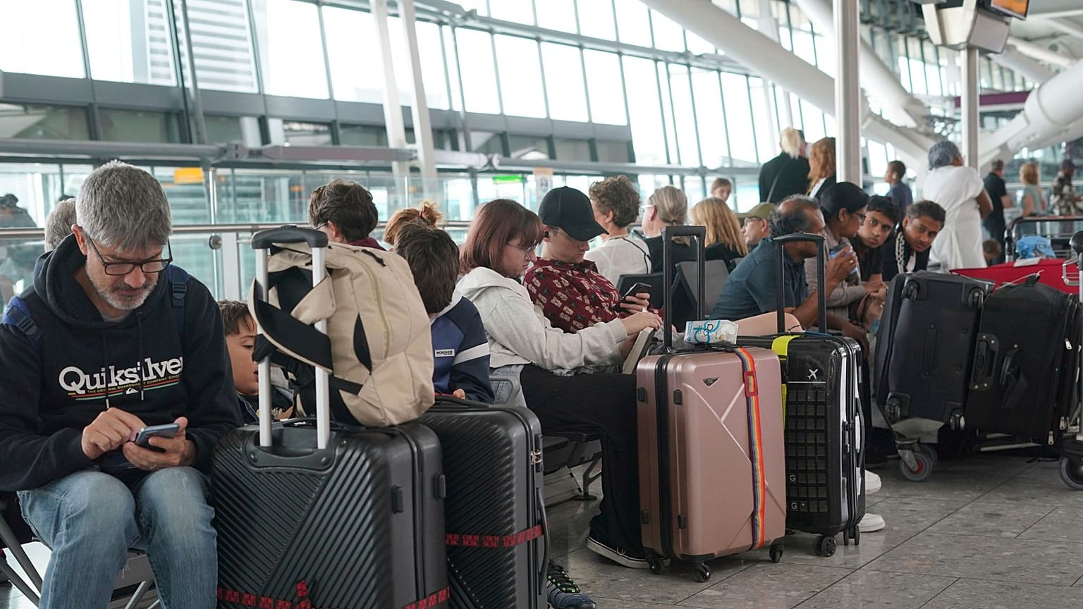 Passengers are seen waiting for delayed flights in London's Heathrow airport, Tuesday, Aug. 29, 2023. 