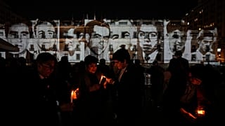 Люди зажигают свечи перед портретами людей, задержанных и исчезнувших во время диктатуры Пиночета в 1973-1990 годах