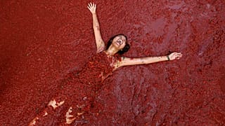 Un juerguista cubierto de pulpa de tomate participa en la batalla alimentaria anual de la "Tomatina