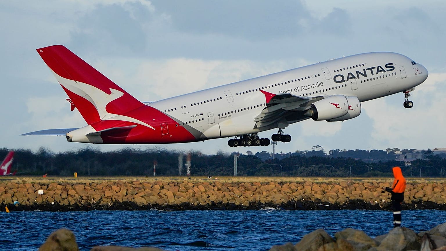 A Qantas A380 takes off from Sydney Airport over Botany Bay as a fisherman stands on breakwater in Sydney, Australia, Monday, Sept. 5, 2022.