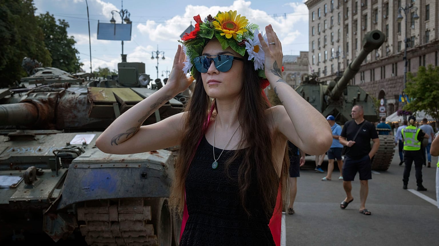 Una donna indossa una ghirlanda di fiori davanti ai carri armati russi catturati, esposti nella centrale Khreshchatyk di Kiev, in Ucraina. 24 agosto 2023