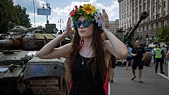 Женщина в цветочной гирлянде перед подбитыми российскими танками, выставленными на Крещатике, 24 августа 2023 года.