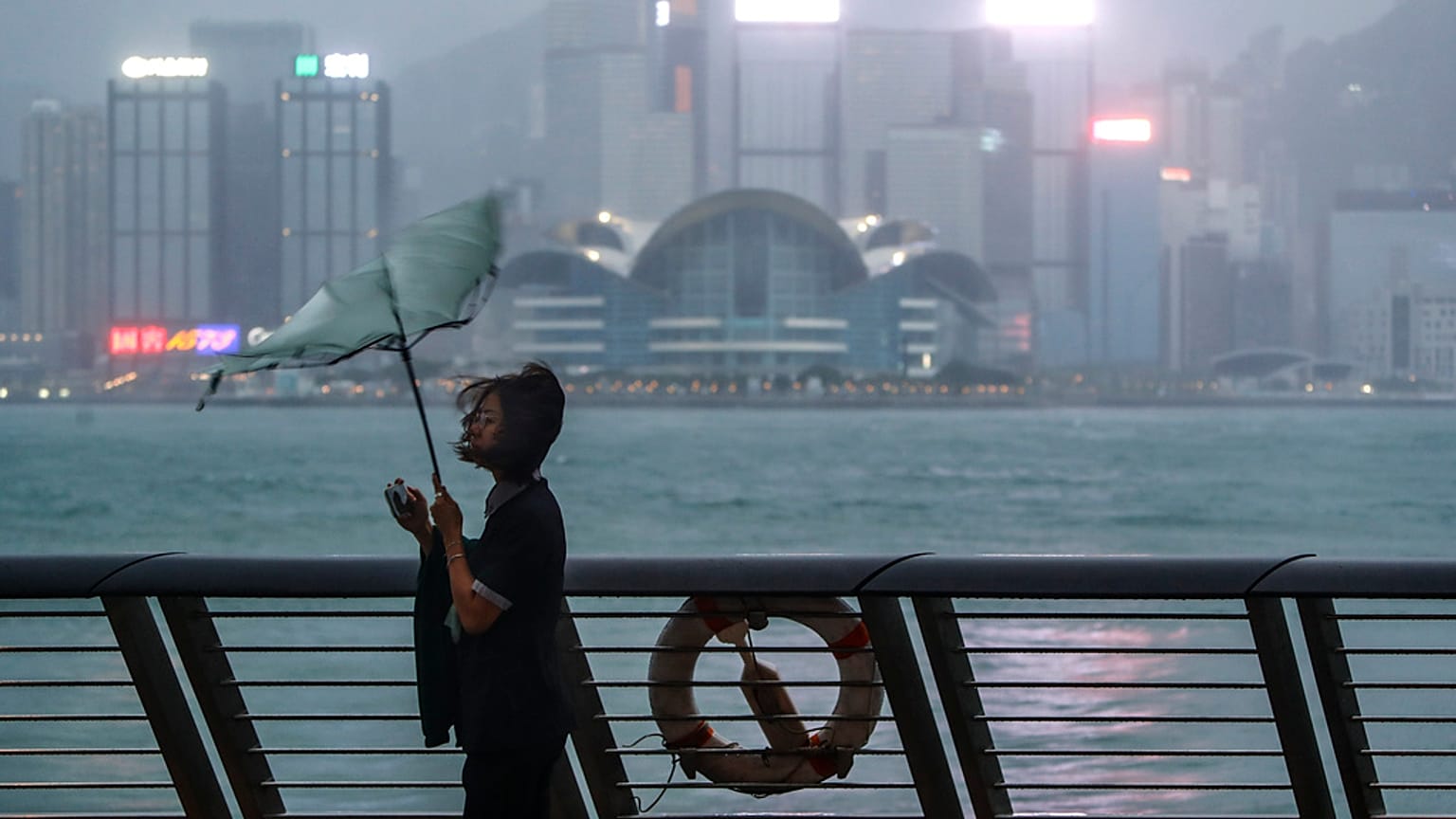 El paraguas de una mujer es arrastrado por el viento a la orilla del mar mientras el tifón Saola azota la ciudad, en Hong Kong, el viernes 1 de septiembre de 2023