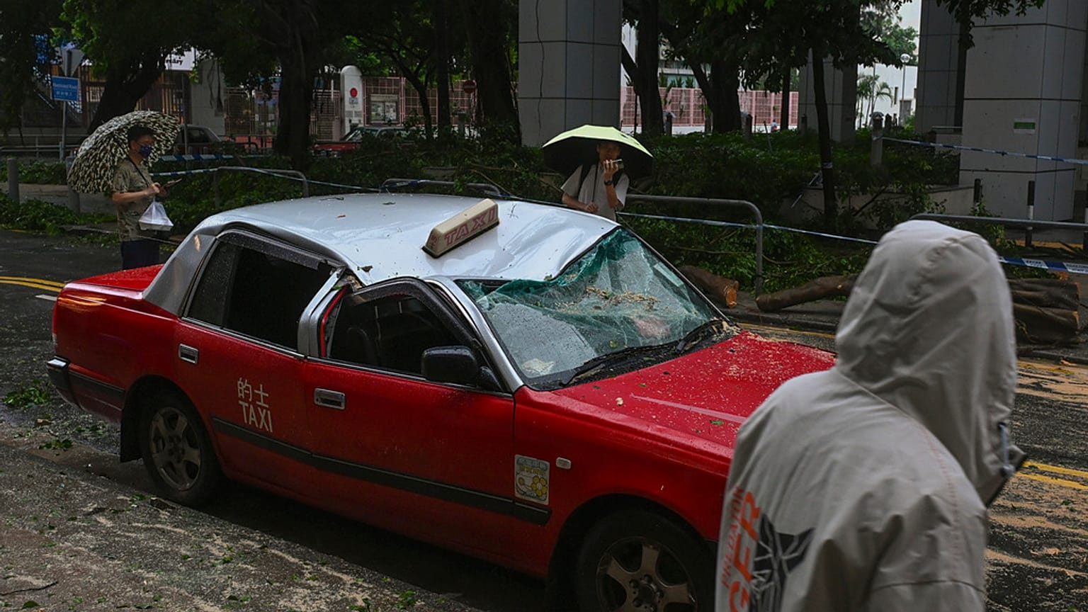 Residents look at a taxi damaged by Typhoon Saola in Chai Wan, Hong Kong, Saturday, Sept. 2, 2023.