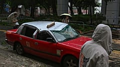 Residents look at a taxi damaged by Typhoon Saola in Chai Wan, Hong Kong, Saturday, Sept. 2, 2023.