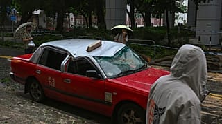Residents look at a taxi damaged by Typhoon Saola in Chai Wan, Hong Kong, Saturday, Sept. 2, 2023.