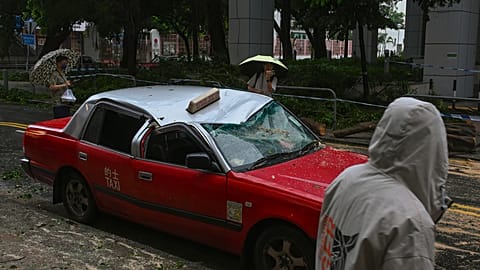 Residents look at a taxi damaged by Typhoon Saola in Chai Wan, Hong Kong, Saturday, Sept. 2, 2023.