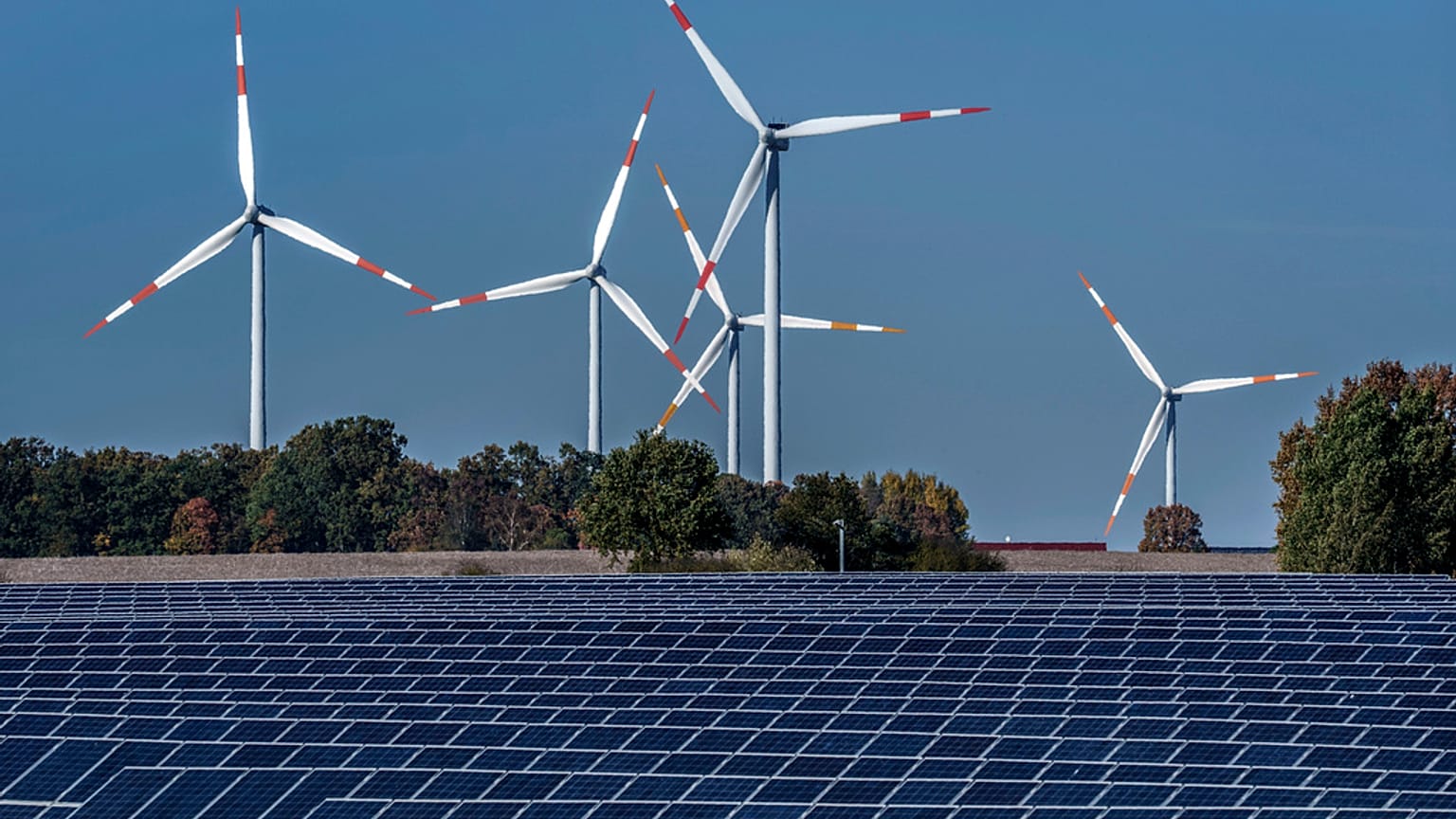 Wind turbines turn behind a solar farm in Rapshagen, Germany.