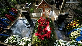 Женщина возлагает цветы на могилу главы группы компаний "Вагнер" Евгения Пригожина на Пороховском кладбище в Санкт-Петербурге, Россия, в среду, 30 августа 2023 года.