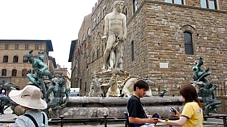 File -Tourists look on by the statue of the Neptune by Italian 16th century artist Bartolomeo Ammannati in Florence's Piazza della Signoria square, 2005
