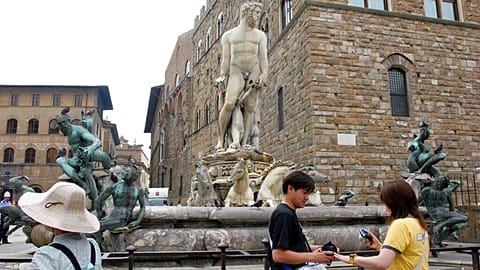 File -Tourists look on by the statue of the Neptune by Italian 16th century artist Bartolomeo Ammannati in Florence's Piazza della Signoria square, 2005