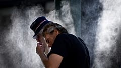 رجل يتبلل بالمراوح المائية التي نشرتها المدينة في وسط المدينة الشرقي بسبب موجة الحر في فانكوفر