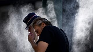 رجل يتبلل بالمراوح المائية التي نشرتها المدينة في وسط المدينة الشرقي بسبب موجة الحر في فانكوفر