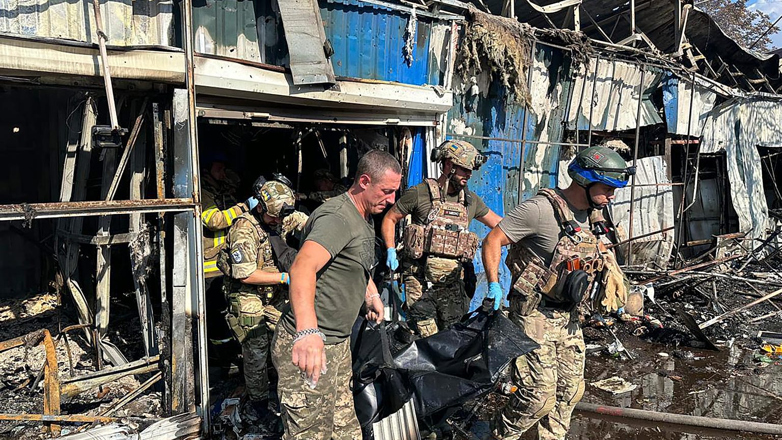 Украинские спасатели выносят тело погибшего 