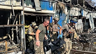 Украинские спасатели выносят тело погибшего