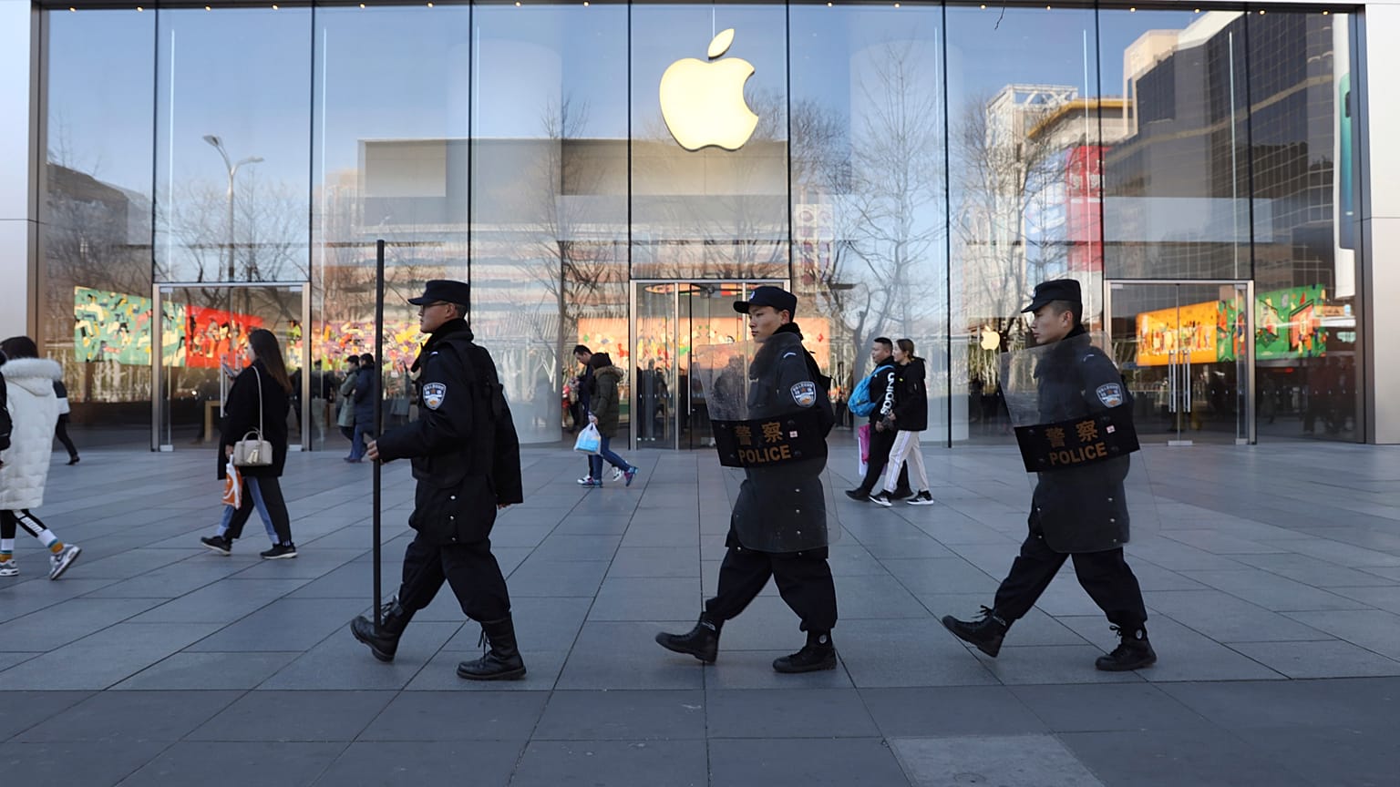 Çinli güvenlik görevlileri Pekin, Çin'deki bir Apple mağazasının önünden geçiyor.